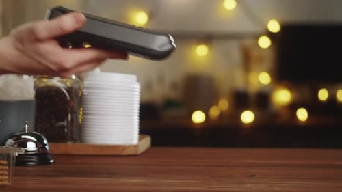 Customer using contactless payment device to pay in a cozy coffee shop