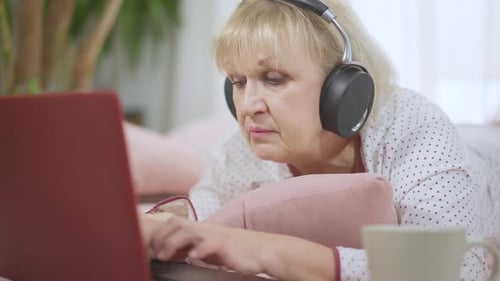 Senior Woman Using Laptop Lying Down