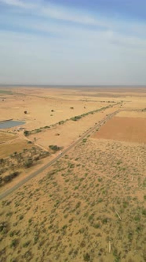 Drone shot of car on Longewala Road amidst desert in Jaisalmer on a sunny day Rajasthan