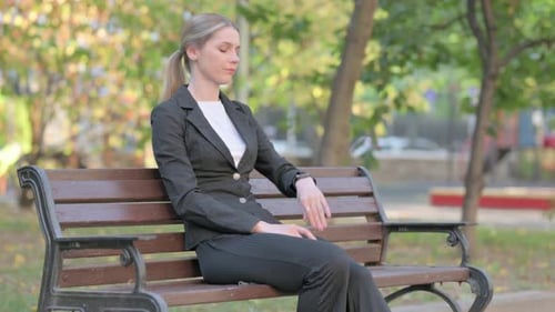 Woman in Suit Checking Watch on Park Bench