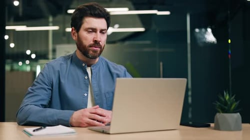 Male Employee Speaking During Video Call on Laptop and Sitting at Office Desk