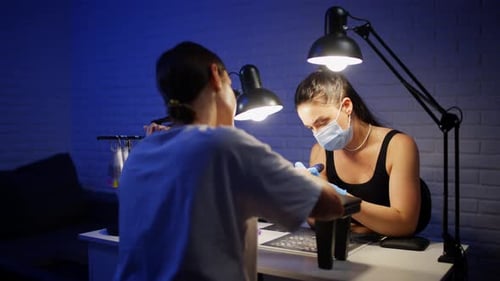 Woman Receiving Manicure with Protective Mask in Salon