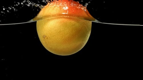 Grapefruit Sinking into Water with Splash on Black