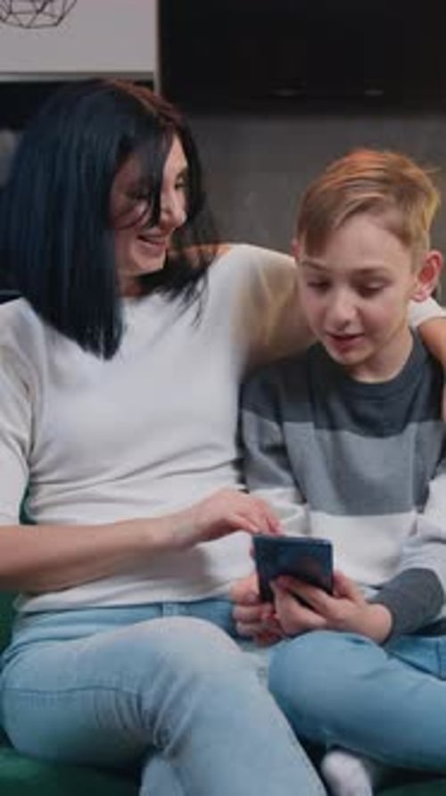Woman and Boy Looking at Phone Together Indoors
