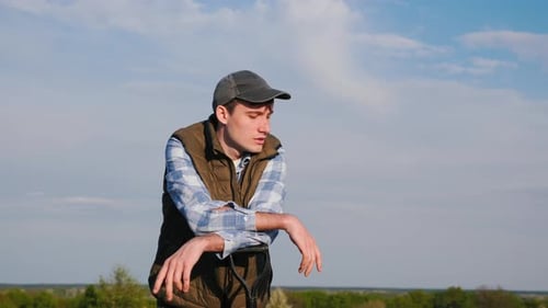 In the Field a Young Farmer is Portrayed Leaning on a Shovel Looking Into the Distance