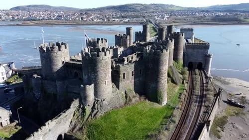 Medieval Conwy castle Welsh market town ruins aerial view historical harbour reversing orbit left
