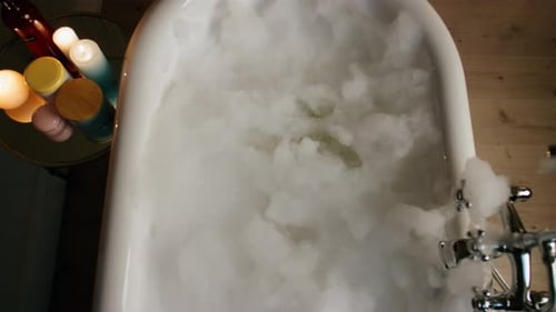 Luxury Bathtub Foamy Water at Candles Room Top View. Bubbles Filled Bath