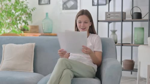 Happy Woman Reads Documents on Sofa