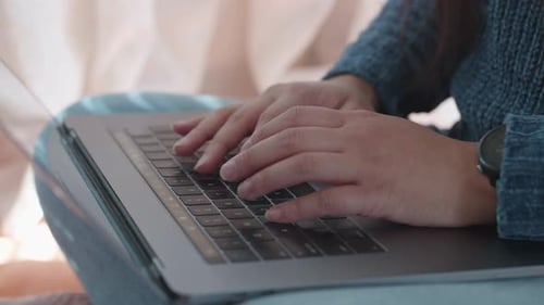 Close up of female hands typing on computer on her lap, slow motion