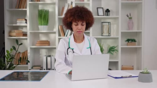 Woman Doctor Working on Laptop in Bright Office
