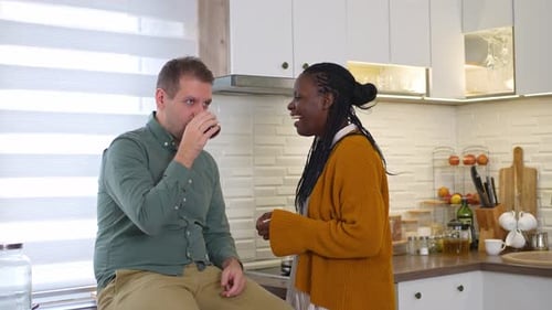 Affectionate Couple Chatting and Drinking in Modern Kitchen