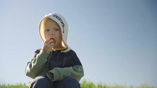 Child Eating Pastry Outdoors on Sunny Day