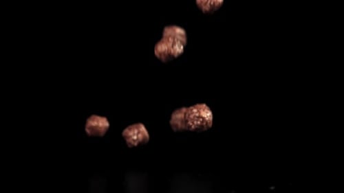 Chocolate Cereal Puffs Falling on Black Background