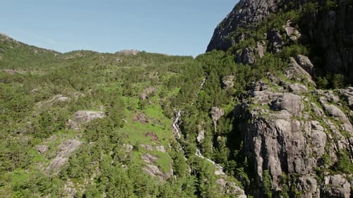 Waterfall Amid Rocky Terrain And Forested Surroundings
