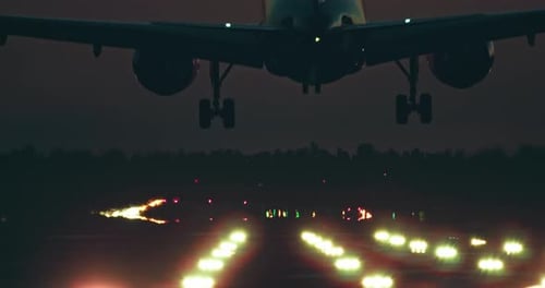 A Passenger Plane Lands on the Illuminated Runway of the Airport at Night