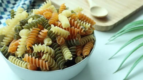 Trockene bunte Pasta in einer Schüssel auf weißem Hintergrund