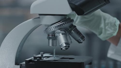 Microscope in Lab with Gloved Hand Using Pipette
