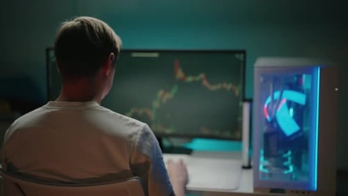 Junger professioneller Händler, männlich, analysiert das Kryptowährungsdiagramm, das auf dem Computerbildschirm angezeigt wird