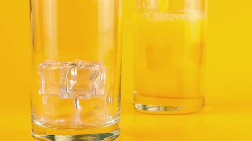 Orange Juice Pouring into Ice Filled Glass