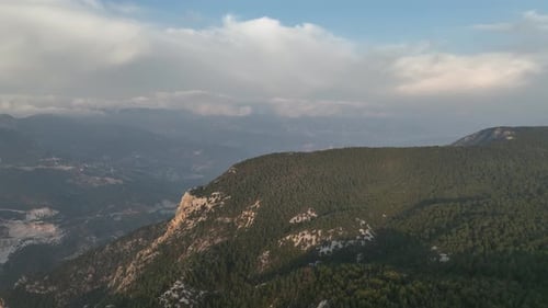 Aerial View Of Foggy Valley Expanse Behind Sloping Mountain Pass In Summer