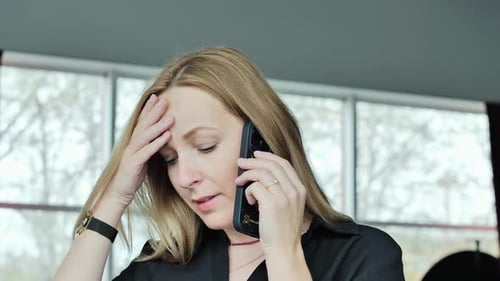 Worried Woman Talking on Mobile Phone Near Office Window - Urban Mood Concept