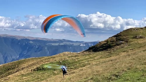 Gleitschirmflieger starten und über Bergen fliegen