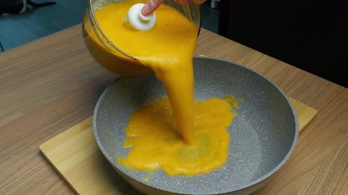 Pouring Orange Liquid Into a Pan