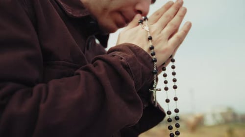Young Adult Praying With Rosary Beads