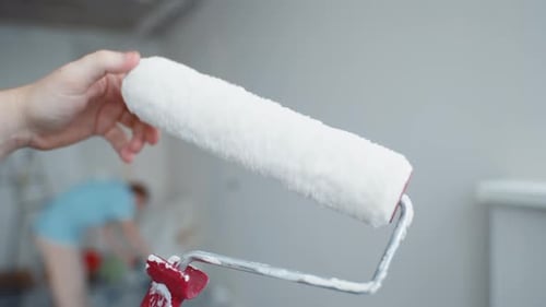 Close Up of Paint Roller with Woman Painting