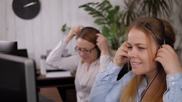 Side View of Two Young Friendly Female Operators Putting on Headsets in ...