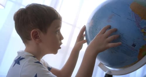 Boy Exploring Globe in Brightly Lit Room