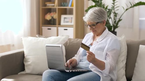 Senior woman shops online using laptop and credit card