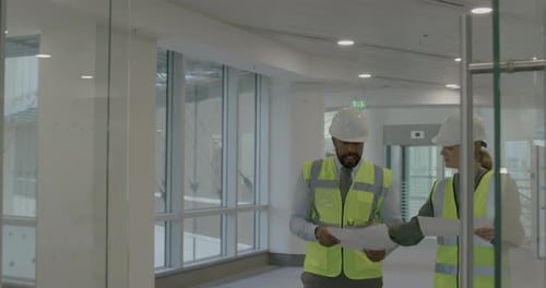 Builder and Architect Walking around New Office and Looking at Blueprint