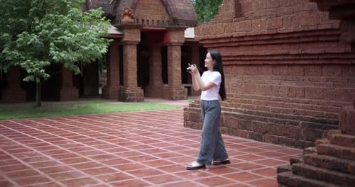 An Asian female tourist walks around the temple grounds and takes photos.