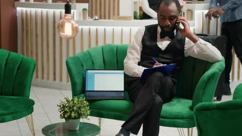 Hotel Employee on Phone Writing on Clipboard