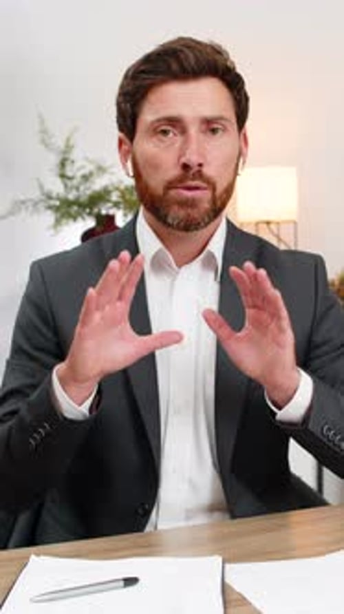 Man in suit explains at desk in office