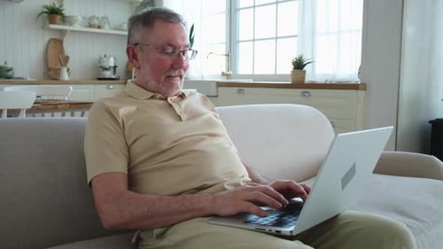 Senior Man Using Laptop at Home on Couch