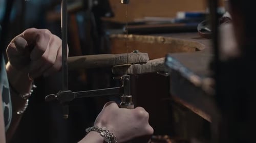 Woman Jeweler Using Saw to Cut Metal