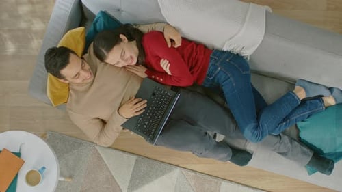 Young Couple Relaxing on Sofa with Laptop