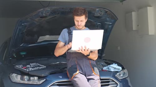 Auto Mechanic Diagnosing Car with Laptop in Garage