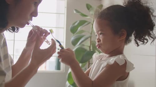 Mother and Child Brushing Teeth in Bathroom