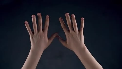 Pair of hands moving against dark background