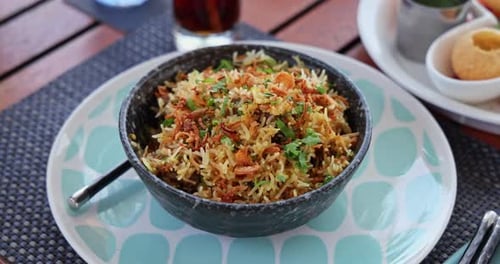 Biryani bowl with fried onions and coriander on restaurant table
