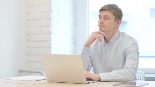 Thoughtful Young Adult Working on Laptop