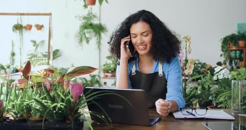 Portrait of african american businesswoman in an apron sitting in own flower store and talking