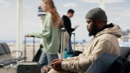 Homme professionnel indépendant tapant sur un ordinateur portable dans la zone d'attente de l'aéroport