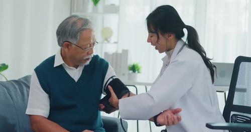 Young Asia female doctor with old man patient using blood pressure consultation in health clinic.
