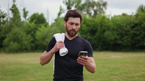 Athletic Man Using Smartphone in Park
