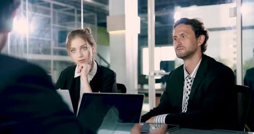 Caucasian male adult professional listening seriously seated beside young female colleague during
