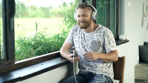Man Listening to Music Indoors by a Window